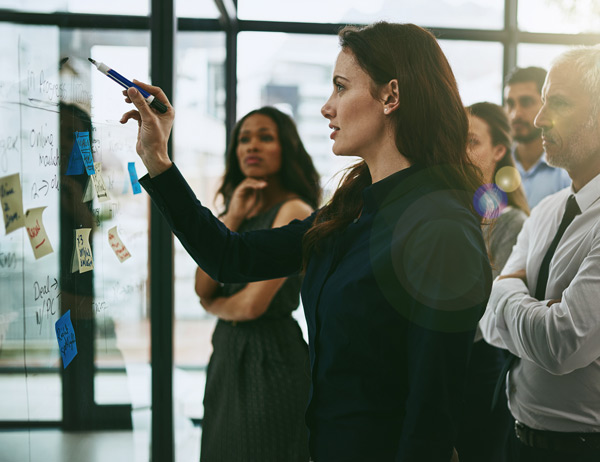 A group of people standing discussing notes on a whiteboard