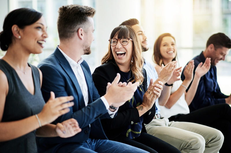 A group of people are clapping and smiling 