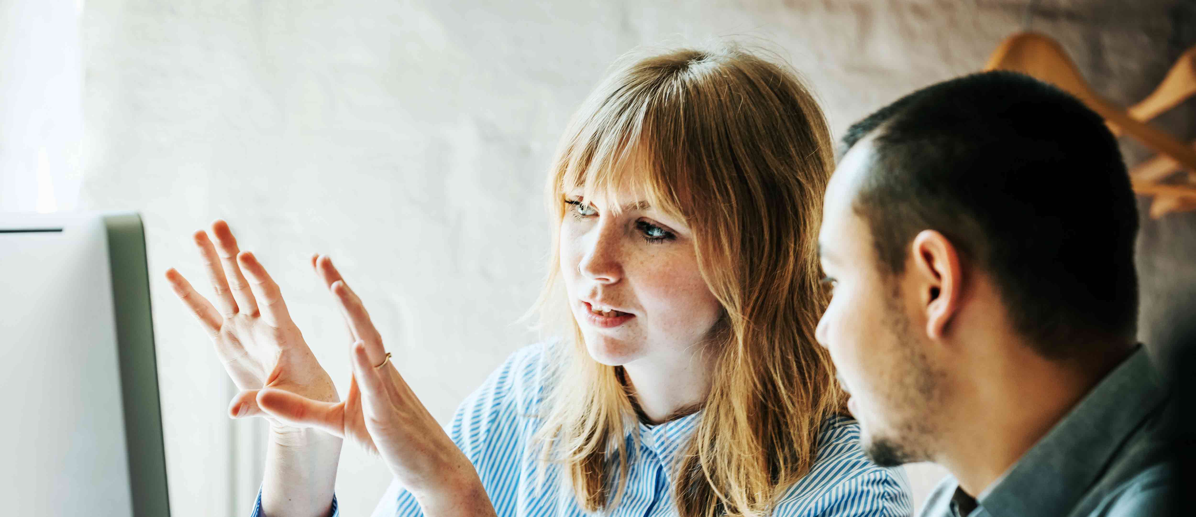 A young employee helps a colleague problem solve at a computer together