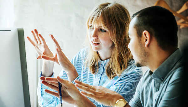 A young employee helps a colleague problem solve at a computer together
