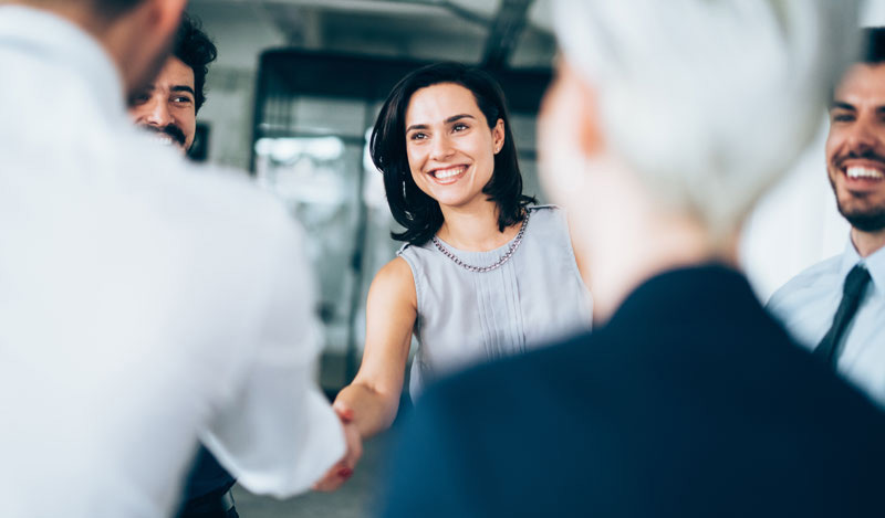 A women shaking hands with colleagues to introduce herself