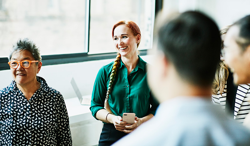A group of people are interacting with each other informally and smiling