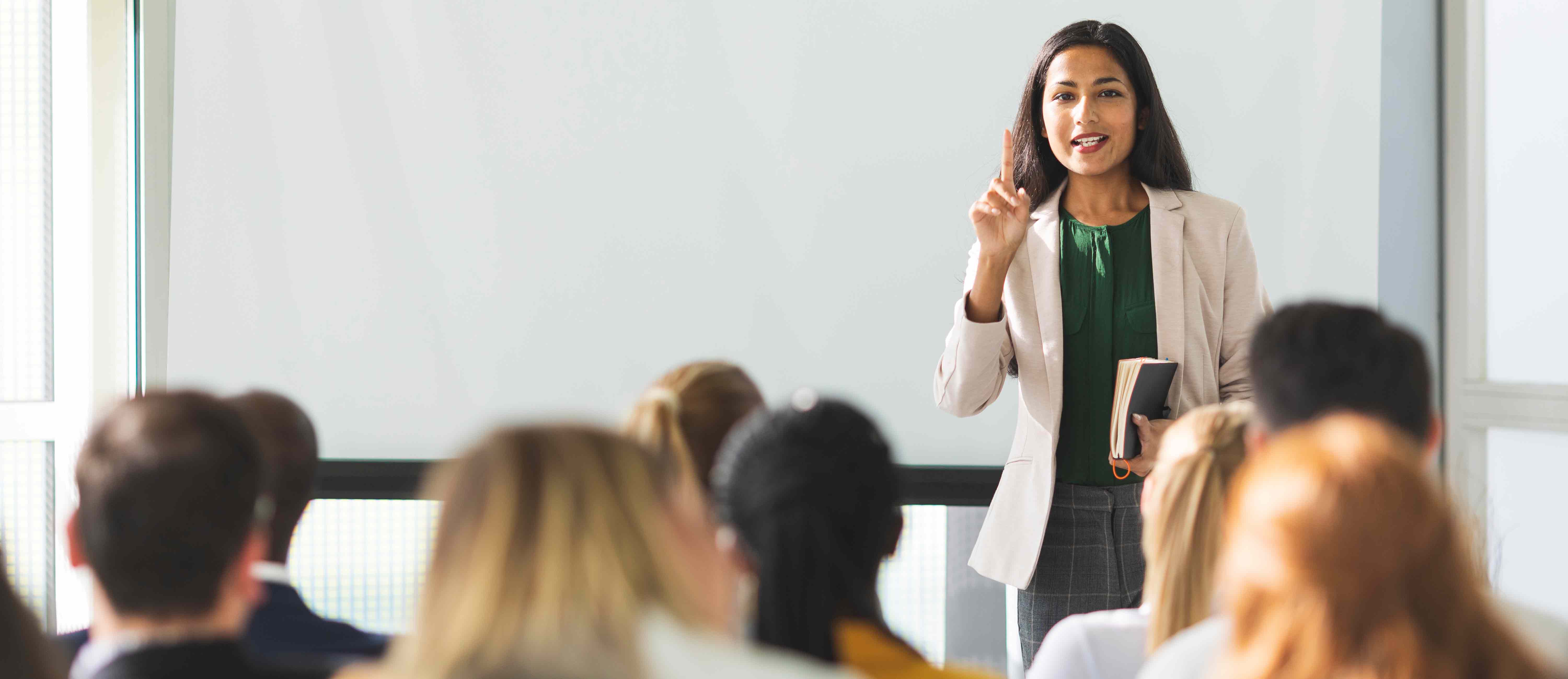 Woman is standing in front of an audience giving a presentation