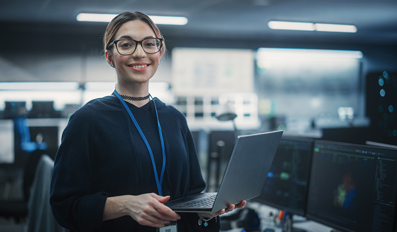 A women smiles holding her laptop 
