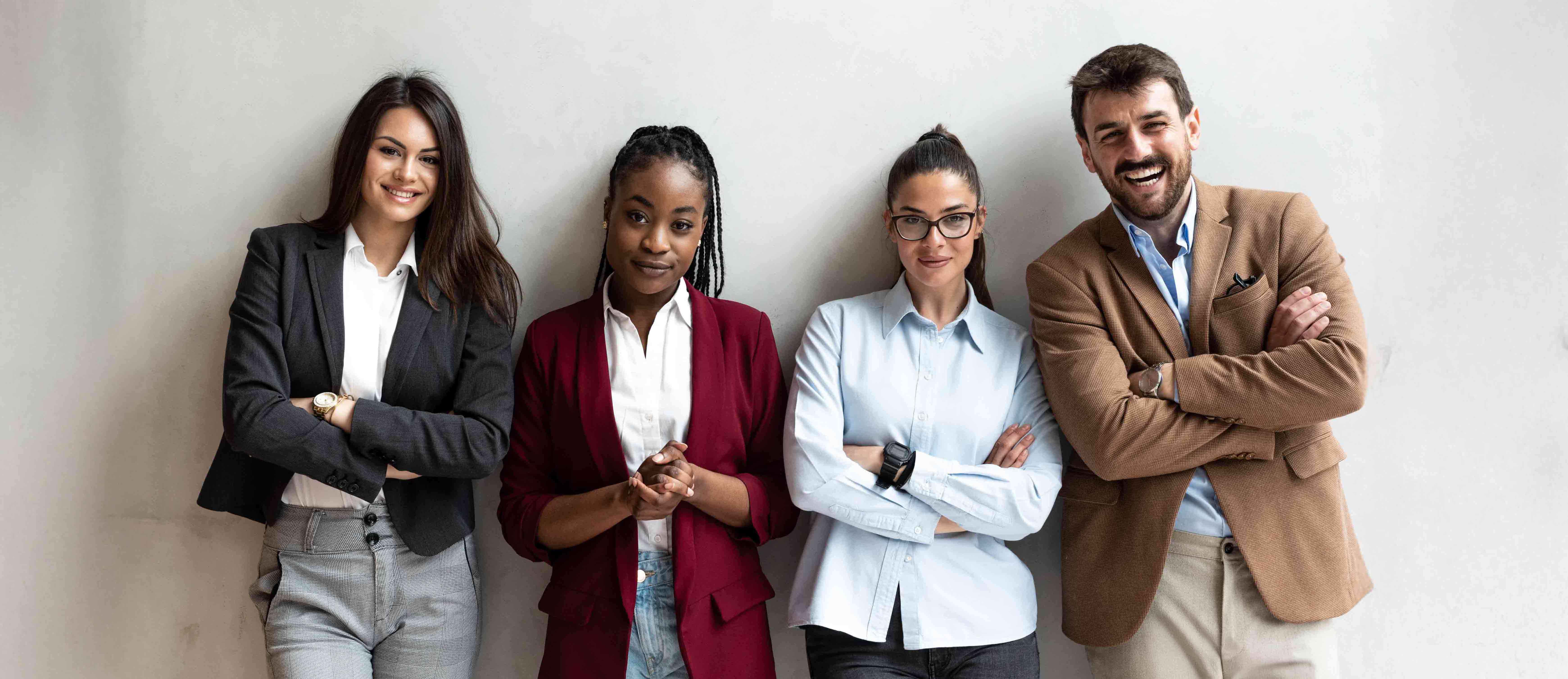Four people line up against wall looking at the camera 